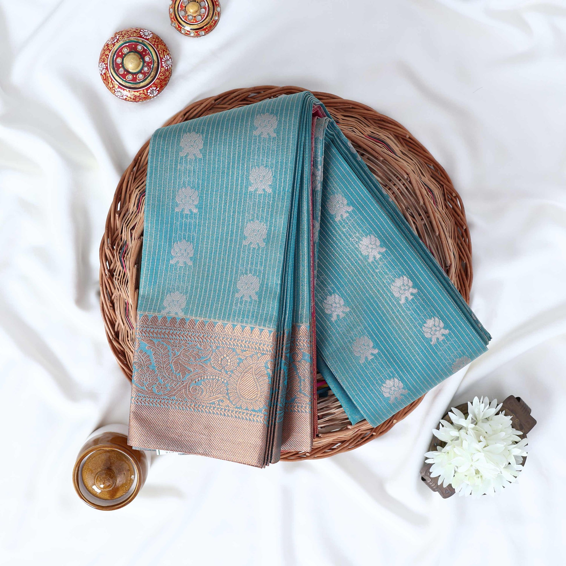 Teal Elampillai silk cotton saree with silver floral zari buttas vertical stripes and contrast zari border folded top view