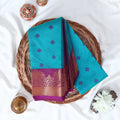 Teal Elampillai silk cotton saree with woven butta motifs and floral zari contrast border folded top view display.