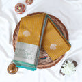 Yellow Elampillai silk cotton saree with silver zari floral buttas vertical stripes and contrast floral zari border folded top view