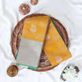 Elampillai silk cotton saree with floral butta checks pattern and floral zari border in yellow top view display.