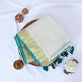 Mul Mul cotton saree with green body gold zari border and green tassels folded top view display
