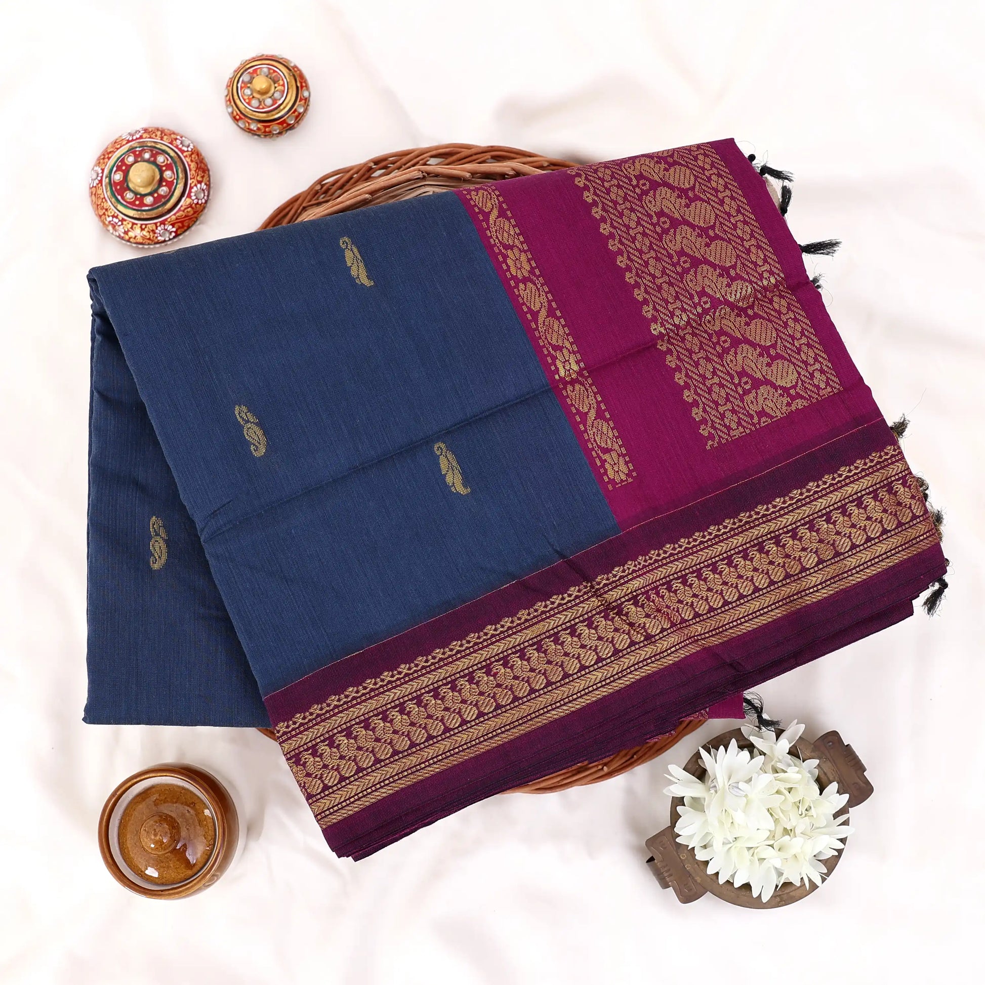 Kalyani Cotton saree with plain deep blue body and maroon zari woven border, folded top view