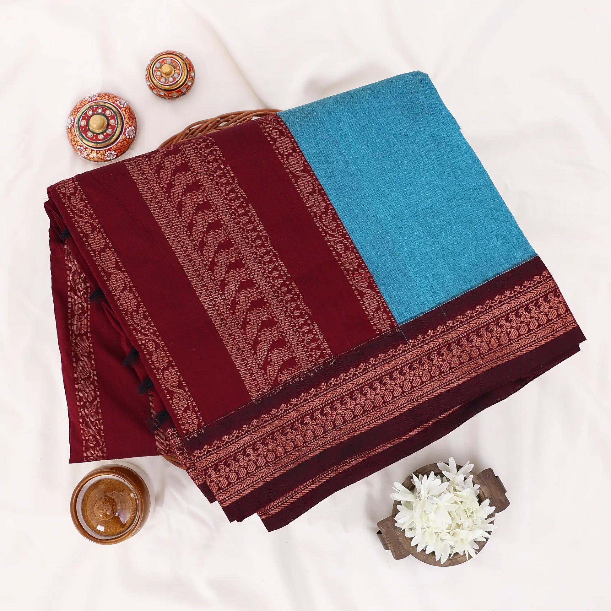 Kalyani Cotton saree with sky blue body and maroon zari woven border, folded top view