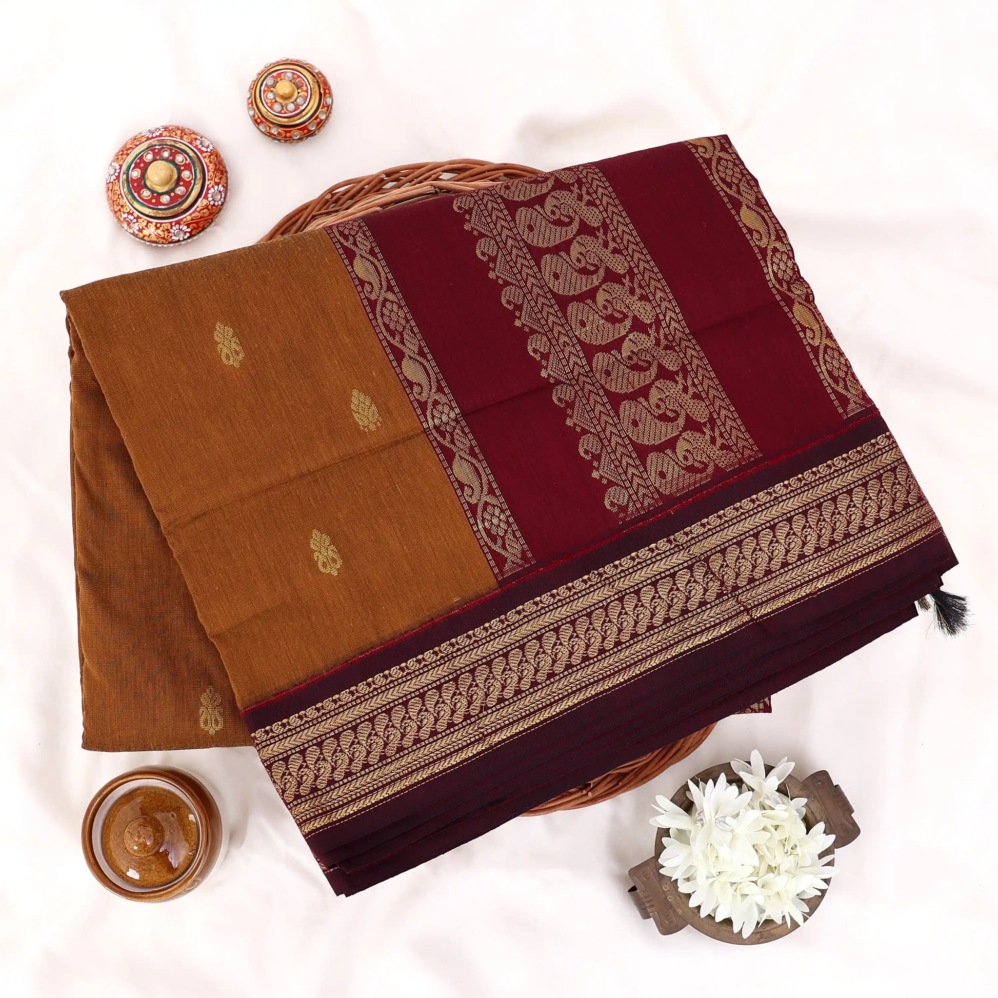 Kalyani Cotton saree with deep brown body and maroon zari woven border, folded top view