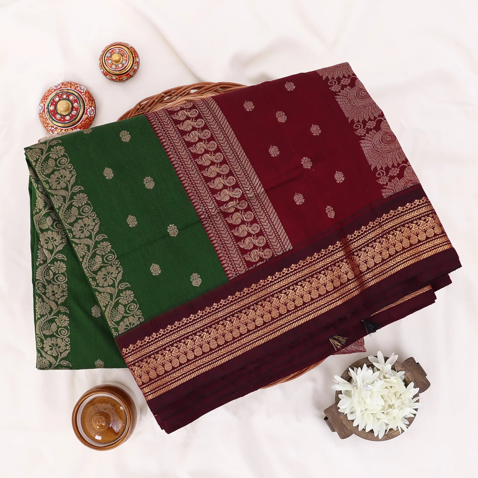 Kalyani Cotton saree with deep green body and maroon zari woven floral border, folded top view