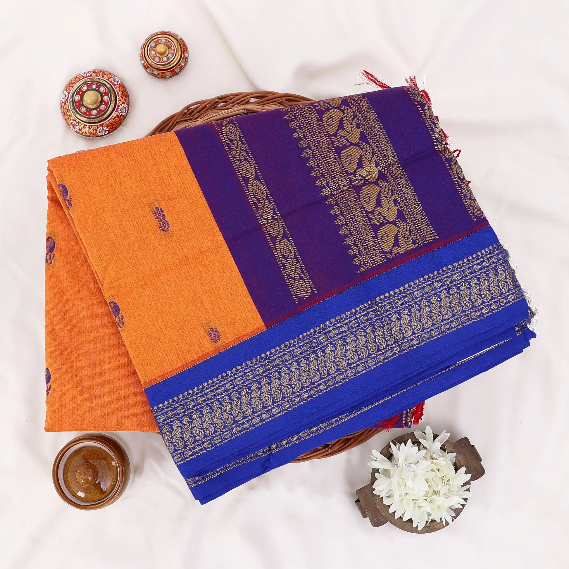 Kalyani Cotton saree with deep orange body and blue zari woven border, folded top view