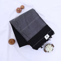 Khadi cotton saree with contrast woven border and tassels in black folded flat lay product view.