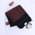 Khadi cotton saree with contrast woven border and tassels in black folded flat lay product view.