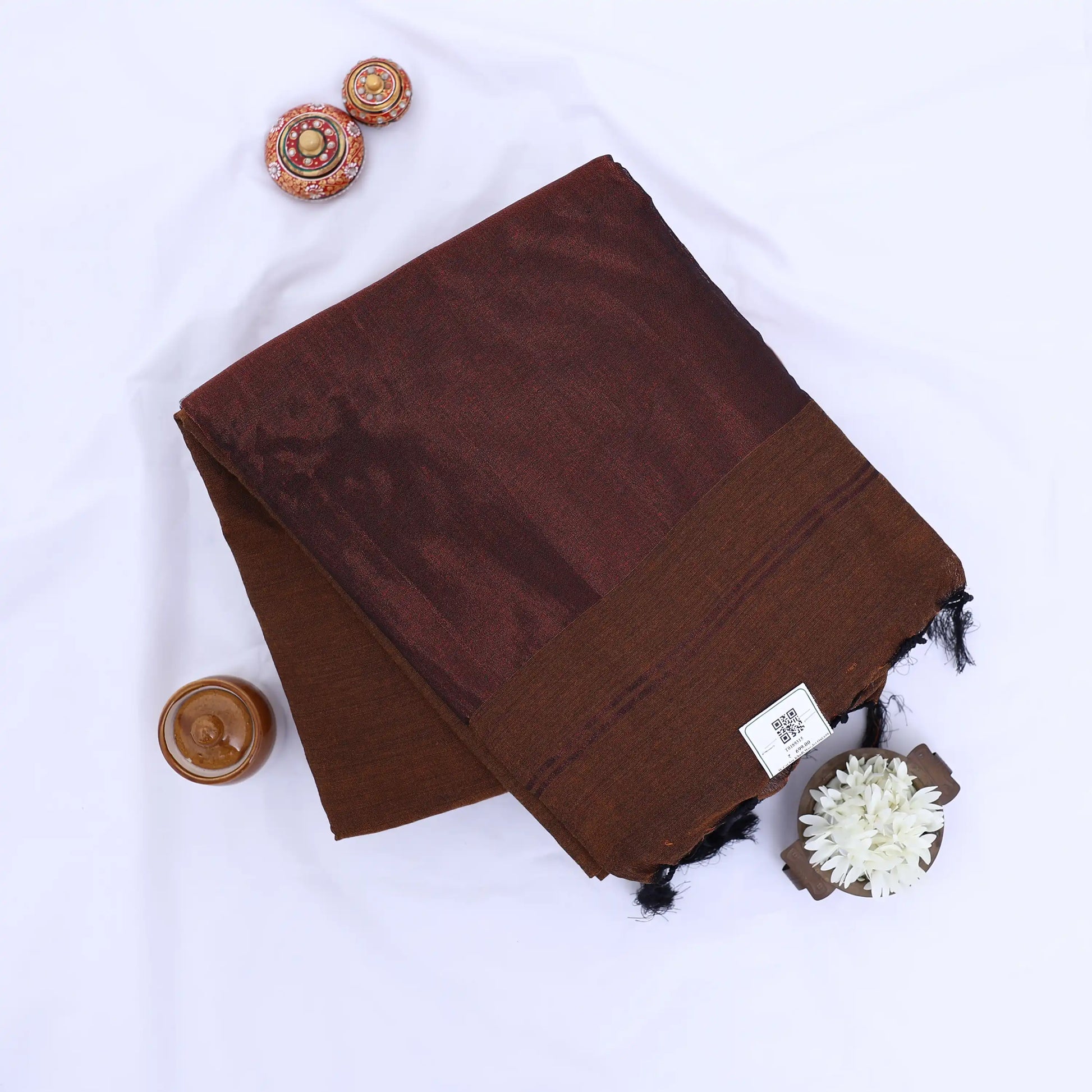 Khadi cotton saree with contrast woven border and tassels in brown folded flat lay product view.