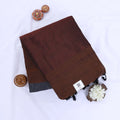 Khadi cotton saree with contrast woven border and tassels in dark brown folded flat lay product view.
