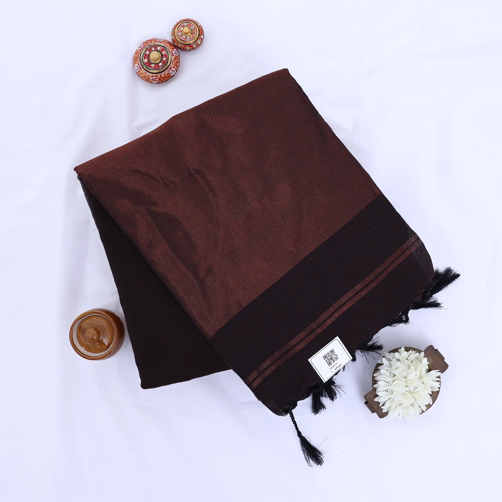 Khadi cotton saree with contrast woven border and tassels in deep brown folded flat lay product view.