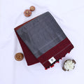 Khadi cotton saree with contrast woven border and tassels in dark maroon folded flat lay product view.