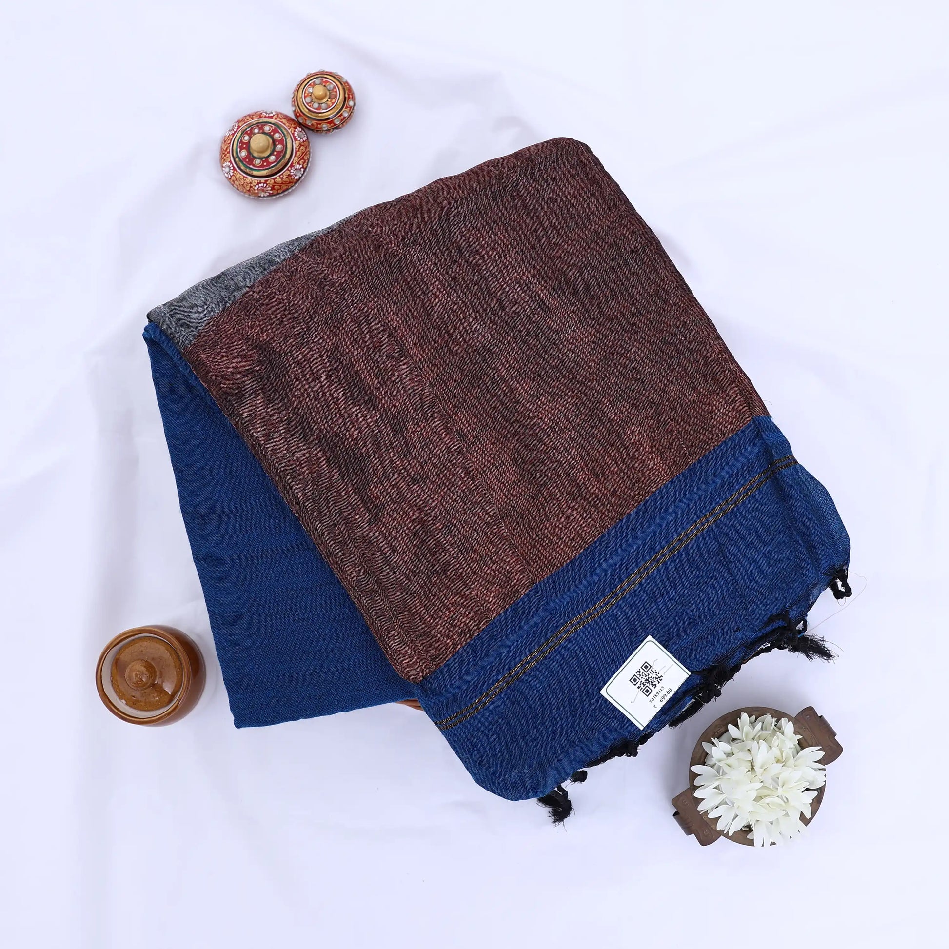 Khadi cotton saree with contrast woven border and tassels in blue folded flat lay product view.