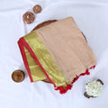 Mul Mul cotton saree with sandal body gold zari border and red tassels folded top view display