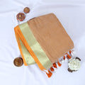 Mul Mul cotton saree with lighrt sandal body gold zari border and orange tassels folded top view display