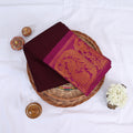 Sungudi cotton saree with gold zari woven border maroon and magenta folded top view on wicker basket