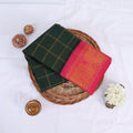 Sungudi cotton saree with gold check pattern and pink peacock zari border in dark green folded top view
