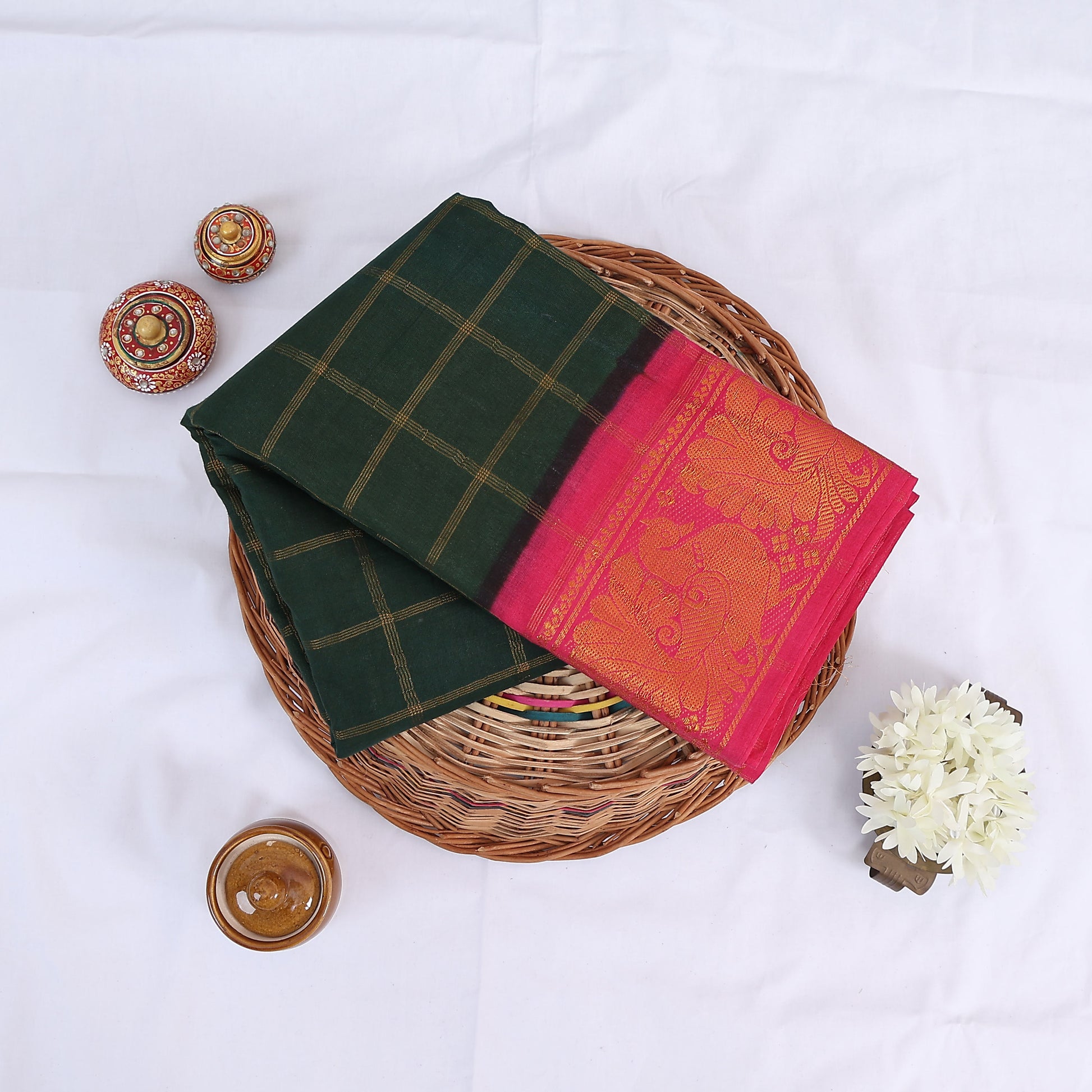 Sungudi cotton saree with gold check pattern and pink peacock zari border in dark green folded top view