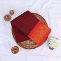 Sungudi cotton saree with gold zari checks body and red peacock motif border folded top view on wicker basket
