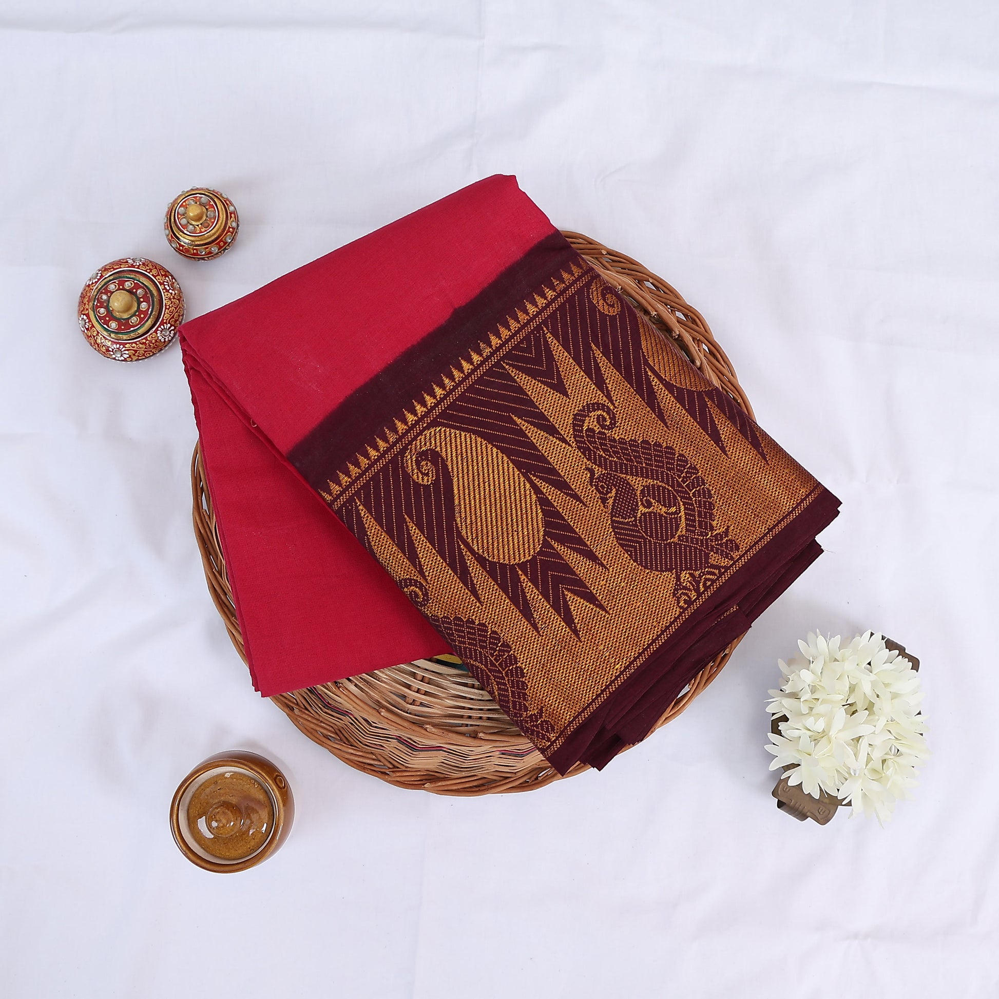 Sungudi cotton saree with vibrant dark pink body and maroon gold zari border folded top view 