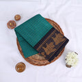 Sungudi cotton saree with gold zari checks body and teal peacock motif border folded top view on wicker basket