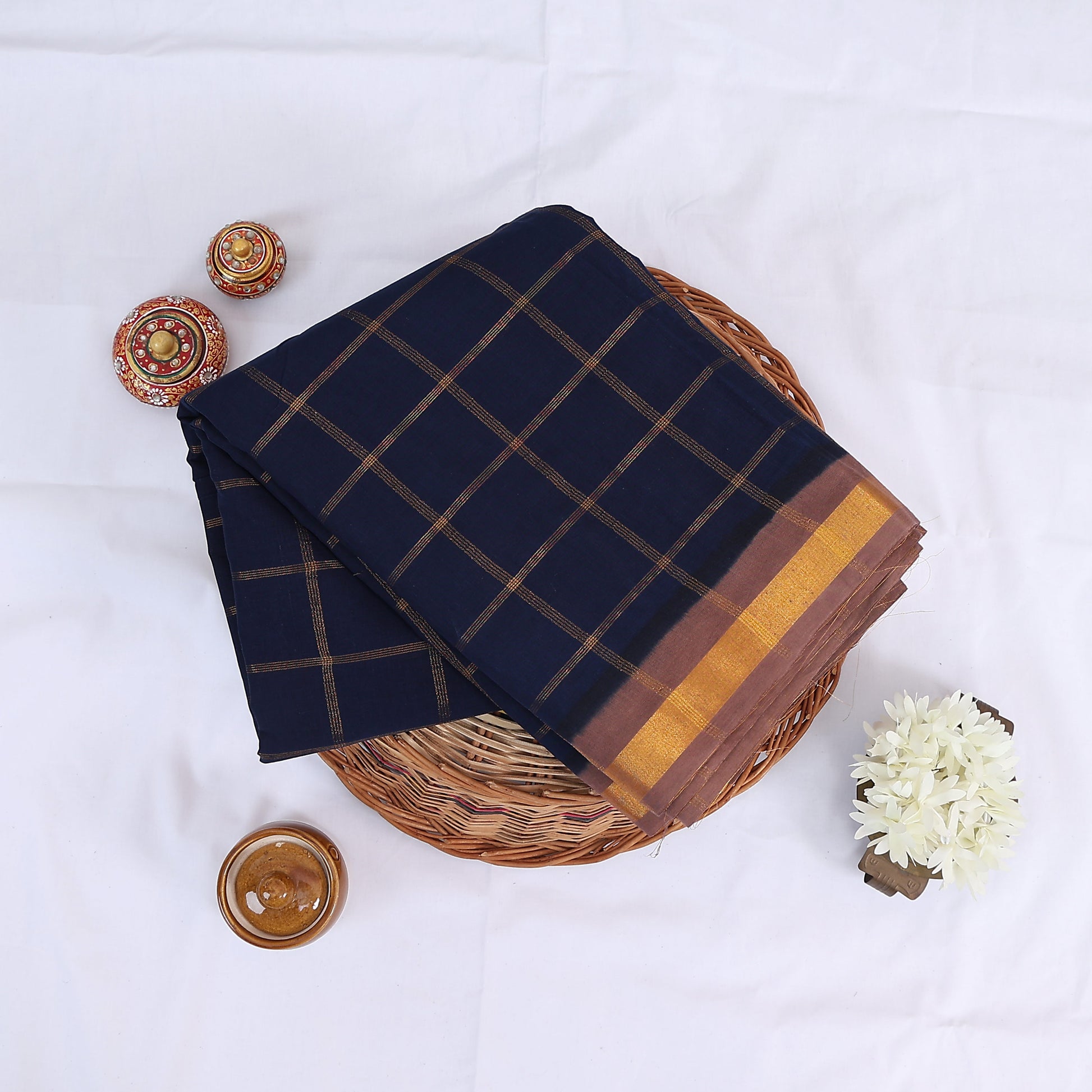 Sungudi cotton saree with zari checked body and contrast zari border in navy blue and brown folded top view 