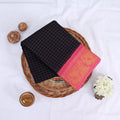 Sungudi cotton saree with gold zari checks body and navy blue peacock motif border folded top view on wicker basket