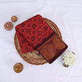 Sungudi cotton saree with traditional elephant motif border in red and maroon folded on a wicker basket top view