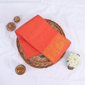 Sungudi cotton saree with gold zari checks body and orange peacock motif border folded top view on wicker basket