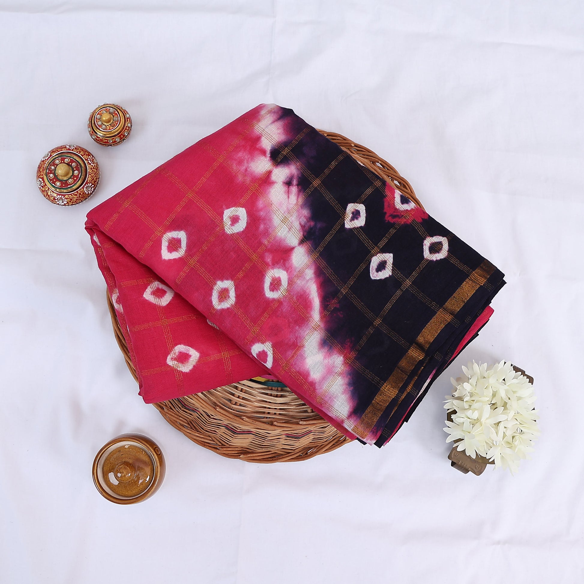 Sungudi cotton saree with white tie-dye motifs pink and navy blue design gold check pattern folded top view
