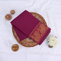 Sungudi cotton saree with gold zari checks body and magenta peacock motif border folded top view on wicker basket