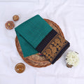 Sungudi cotton saree with gold zari checks body and blue peacock motif border folded top view on wicker basket