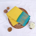 Sungudi cotton saree with gold zari checks body and Yellow peacock motif border folded top view on wicker basket