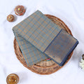 Venkatagiri cotton saree with blue zari border light blue checked pattern and gold motifs folded top view.