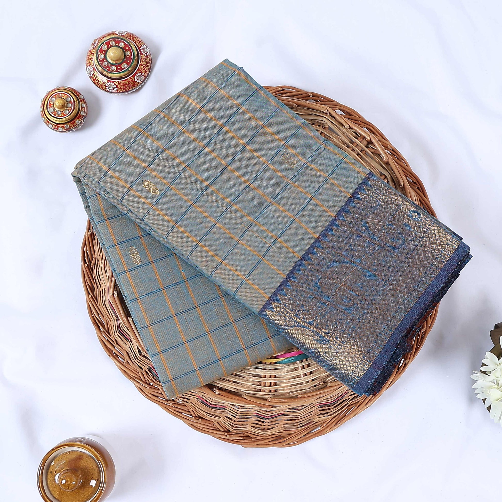 Venkatagiri cotton saree with blue zari border light blue checked pattern and gold motifs folded top view.