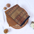 Venkatagiri cotton saree with gold zari floral and elephant border in brown folded top view on wicker basket.