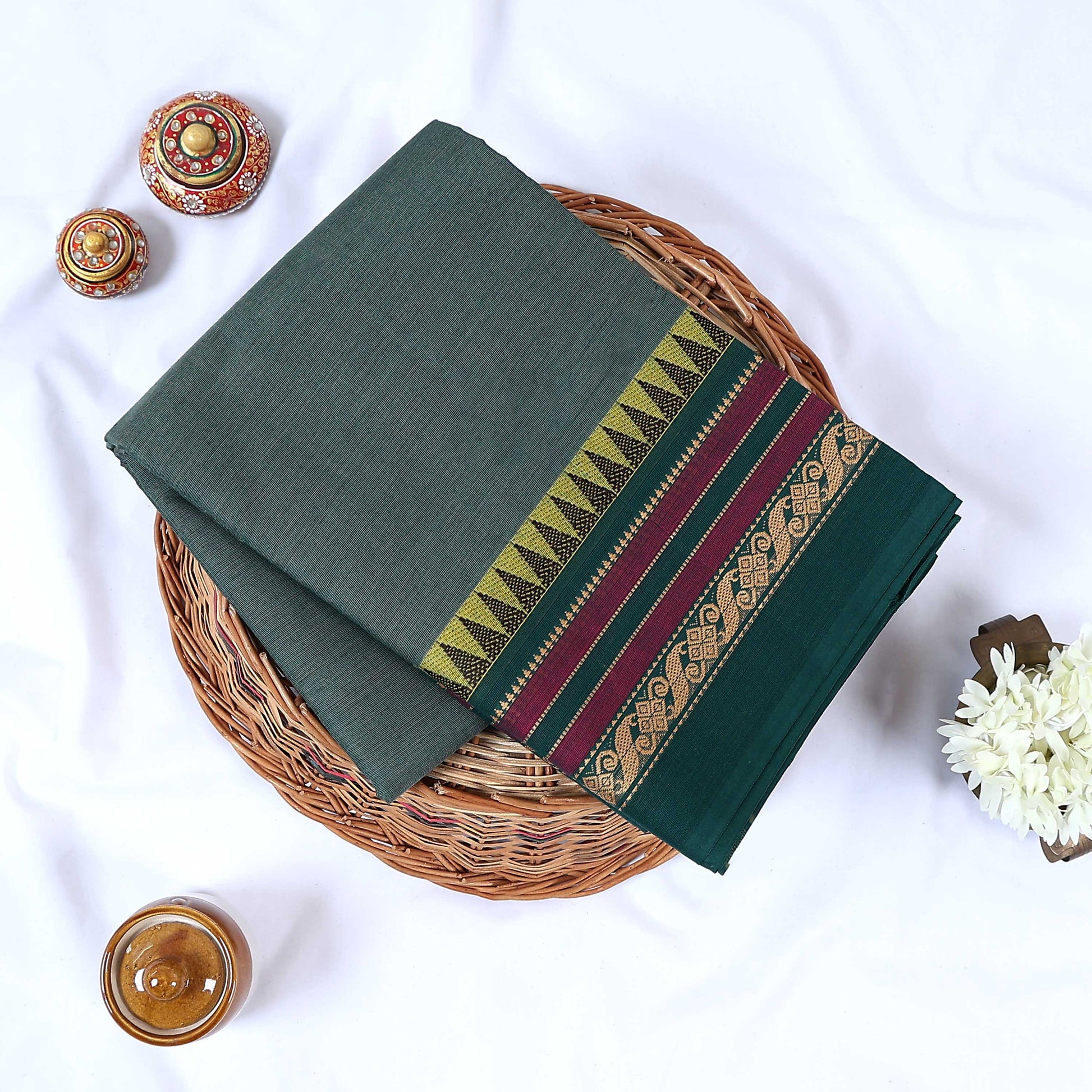 Dark green Venkatagiri cotton saree with multicolor geometric zari woven border folded flat lay front view.