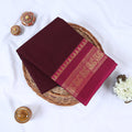 Venkatagiri cotton saree with purple body magenta peacock zari border folded front view on wicker basket