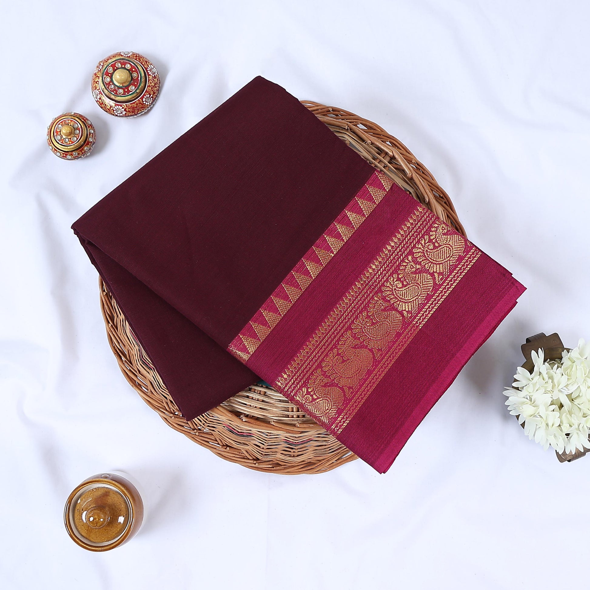 Venkatagiri cotton saree with purple body magenta peacock zari border folded front view on wicker basket