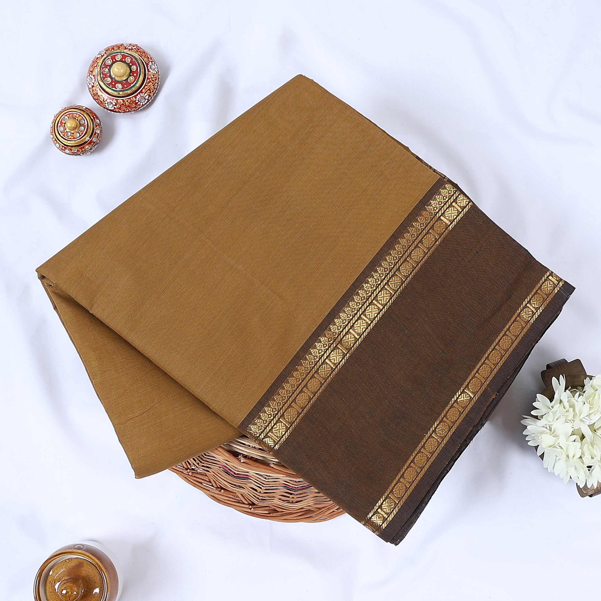 Venkatagiri cotton saree with light brown body and dark brown gold zari geometric border folded top view.