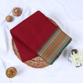 Maroon Venkatagiri cotton saree with green and gold zari woven border folded flat lay front view.