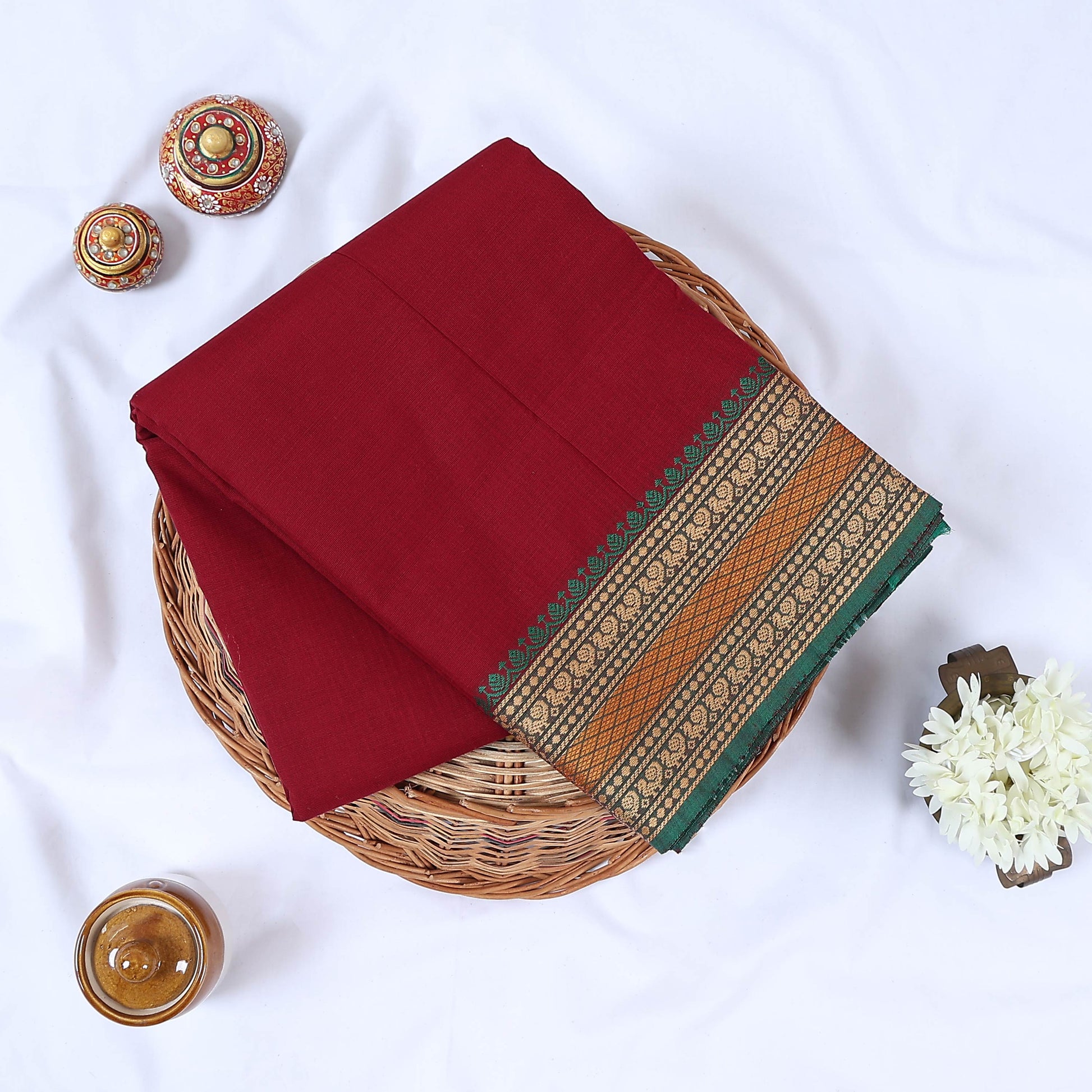 Maroon Venkatagiri cotton saree with green and gold zari woven border folded flat lay front view.