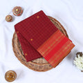 Venkatagiri cotton saree with gold zari checked body and ornate border in maroon and red folded top view on wicker basket.