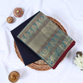 Venkatagiri cotton saree with gold zari floral and elephant border in navy blue folded top view on wicker basket.