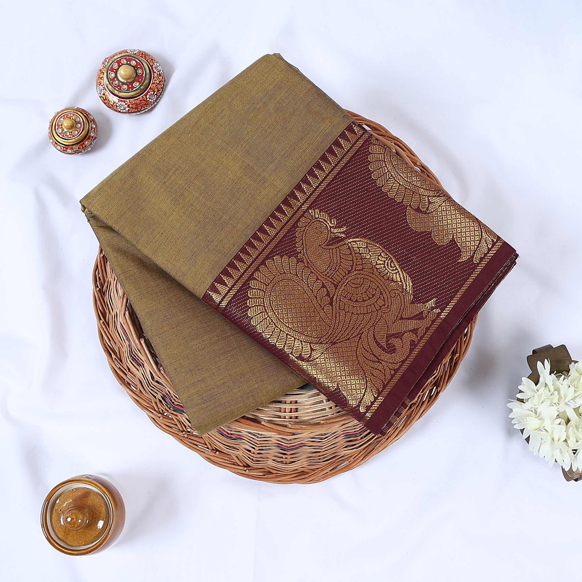 Venkatagiri cotton saree with olive green body and maroon gold zari peacock border folded top view.