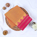 Orange Venkatagiri cotton saree with pink zari temple border folded flat lay front view.