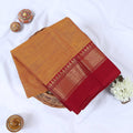 Orange Venkatagiri cotton saree with maroon zari woven border folded flat lay front view.