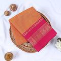 Venkatagiri cotton saree with gold zari peacock border in orange and pink folded top view on wicker basket