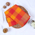Venkatagiri cotton saree with orange, yellow and red checkered pattern and gold zari border folded top view.