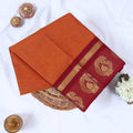 Venkatagiri cotton saree with orange body and maroon gold zari paisley border folded front view.